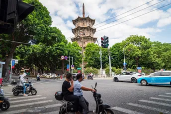 一些人在城市街道上骑着滑板车和摩托车 路上有汽车驶过。