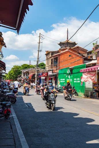 许多人在城市街道上骑摩托车 街道两旁有建筑物。