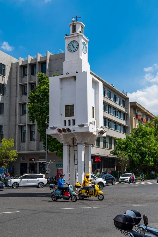 城市中的一条街道 有汽车、摩托车和一座高大的白色钟楼。