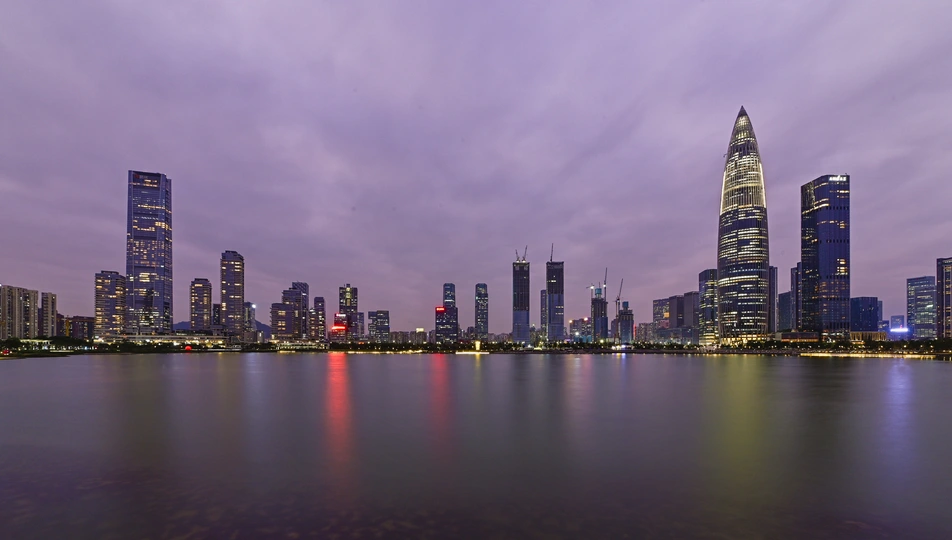 暮色或夜晚的城市 摩天大楼和其他建筑在紫色的天空中熠熠生辉。