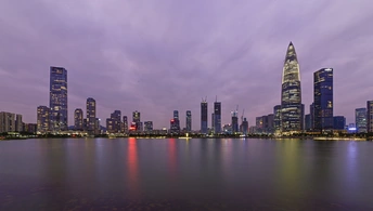 暮色或夜晚的城市 摩天大楼和其他建筑在紫色的天空中熠熠生辉。