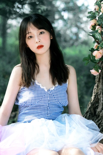 一个穿着蓝色连衣裙的年轻女子坐在森林里的树上