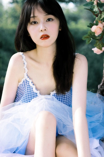 一个穿着蓝色连衣裙的年轻女子坐在树下