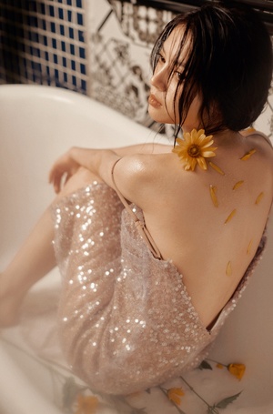 一位年轻女子坐在浴室的浴缸里 穿着一件上面有花的连衣裙