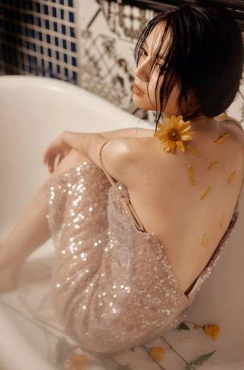 一位年轻女子坐在浴室的浴缸里 穿着一件上面有花的连衣裙