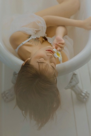 一个躺在白色浴缸里的年轻女人 头发在浴缸里