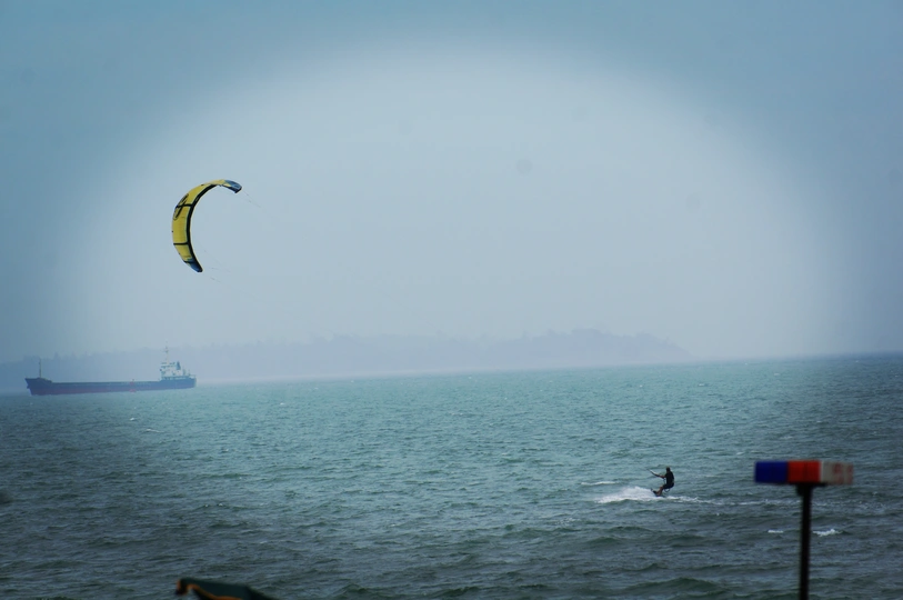 一个人在海洋上冲浪 天空中有一艘大型船