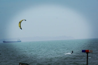 一个人在海洋上冲浪 天空中有一艘大型船
