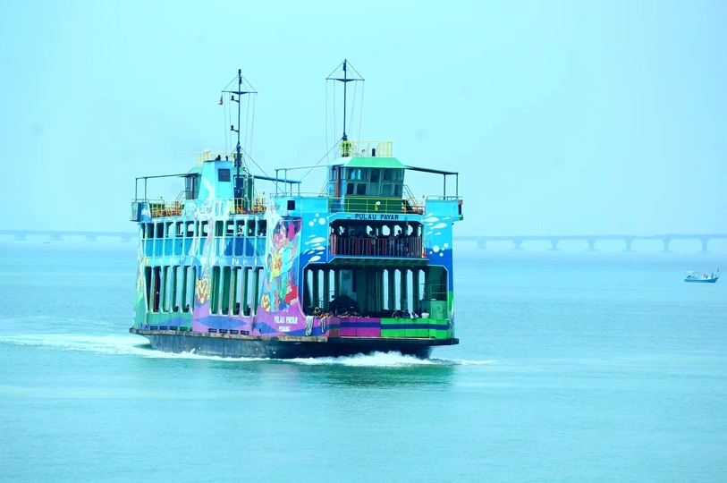 一条色彩斑斓的渡船穿越一大片蔚蓝的水域 靠近一座桥。