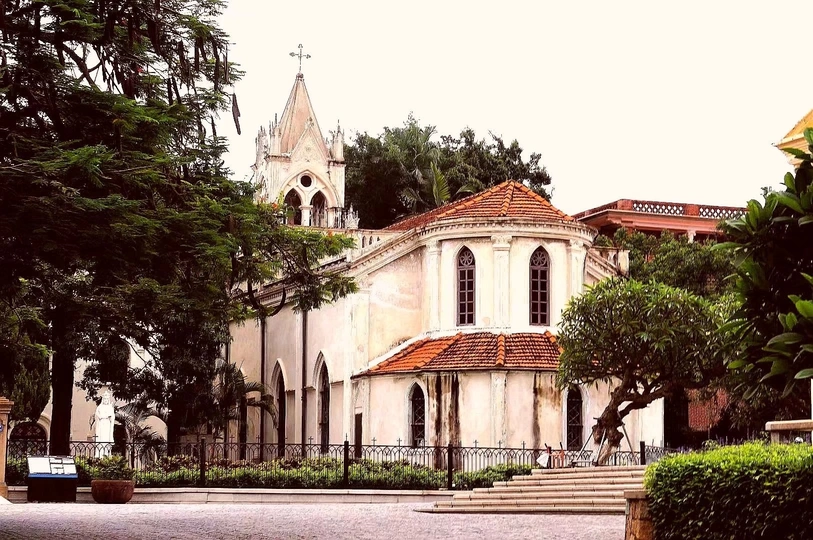 一座古老的白色教堂 位于一排树木环绕的街道上。