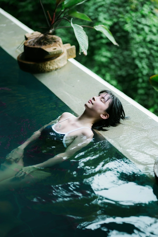 一个年轻女子躺在游泳池里 在水里漂浮。