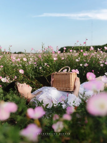 一位女性躺在花丛中 手里拿着篮子。