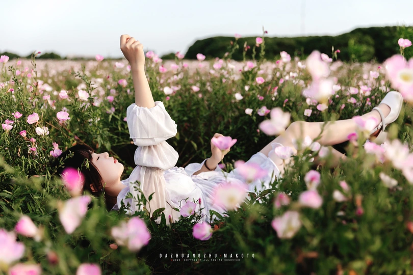 一个穿着白色裙子的女人躺在花丛中