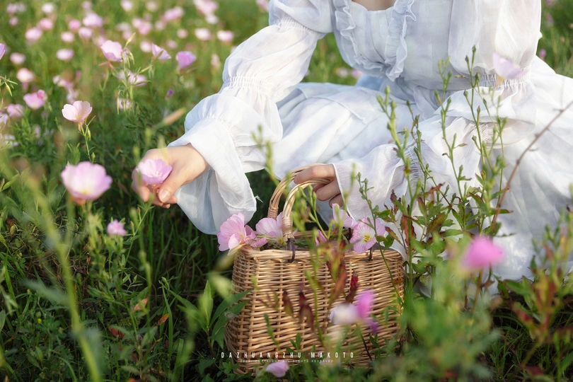 一位穿着白裙子的年轻女子在田地里 picking 花朵 小女孩坐在草地上。