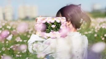 一位年轻女子在田野中拿着白花 自拍她的脸