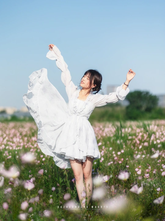 一位穿着白色连衣裙的年轻女子穿过一片花田