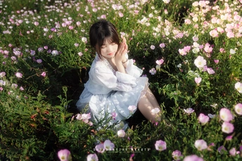 一个小女孩穿着白色裙子坐在花丛中