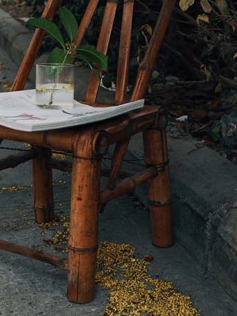 一把木椅子坐在人行道旁边 一张桌子上有玻璃杯和水 还有一盆植物。