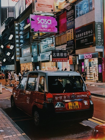 夜晚的城市街道 一辆红色的货车停在路边 人们沿着街道驶过。
