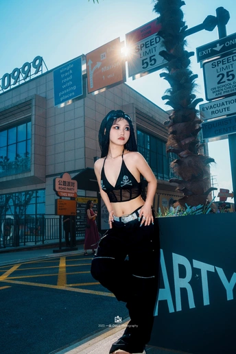 一位穿着黑色裤子的年轻女子站在滑板上在街上。