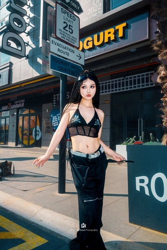 一位全黑衣着的女人站在城市街道的人行道上。