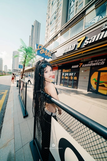 一位长发女孩靠在城市街道的围栏上