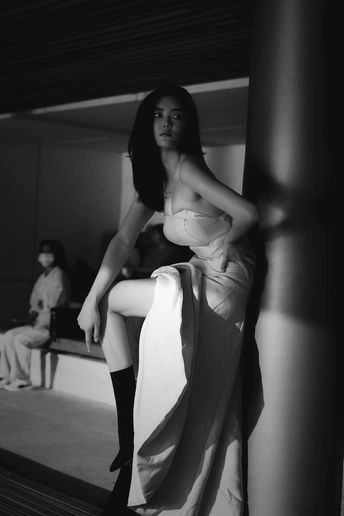 一个穿白色连衣裙的黑白色女人靠在柱子上