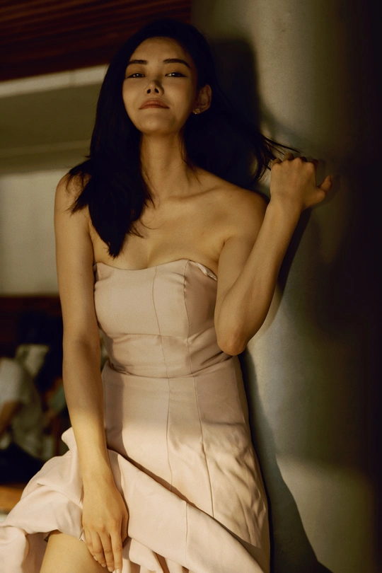 一个穿着白色连衣裙的年轻女子靠在墙上