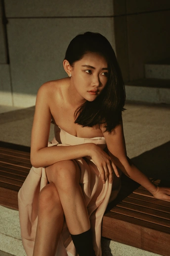 一个穿着白色连衣裙的年轻女子坐在木凳上 双腿交叉