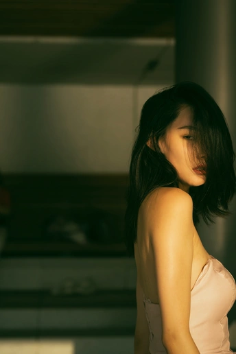 一位穿着白色连衣裙的年轻女子站在壁炉前