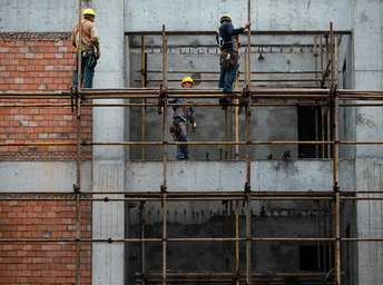 站在脚手架上的男性在建筑工地上工作