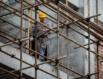 站在脚手架上在建筑工地工作的男子