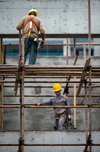 站在脚手架上的男子正在施工中的建筑上工作