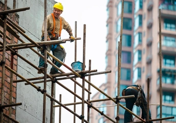 一位男子在高层建筑的施工现场外搭脚手架的照片
