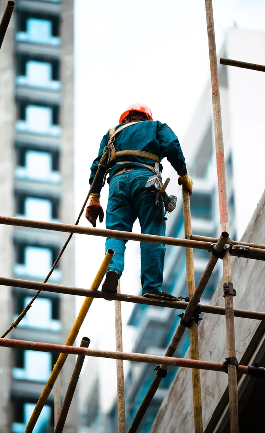 一名男子在高层建筑外搭脚手架 另一名工人站在附近。