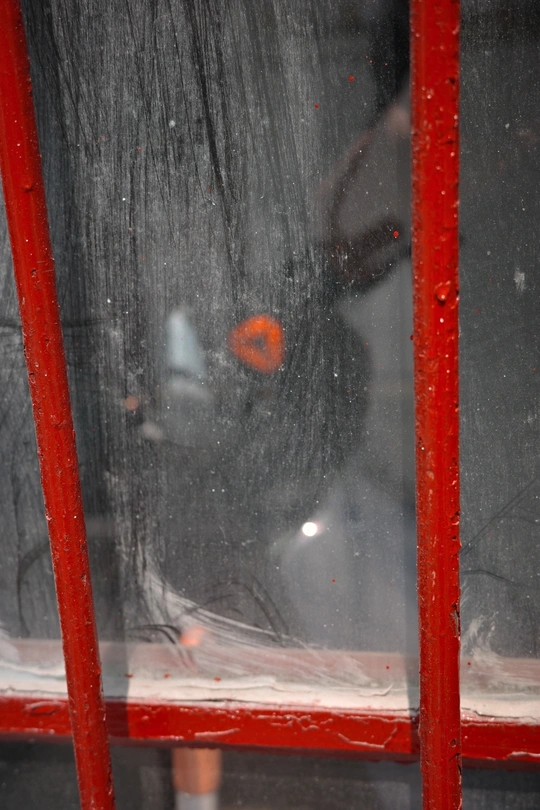 一个红色的电话亭 有一个人带着伞的倒影