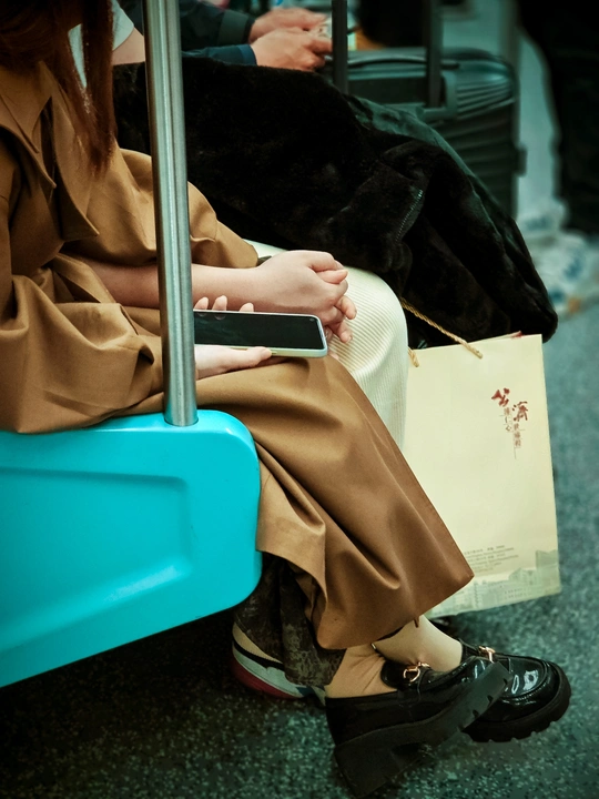 一位女士坐在公交车上 带着行李 正在看手机。