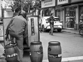 一个站在人行道旁边 旁边有桶和垃圾箱的男人