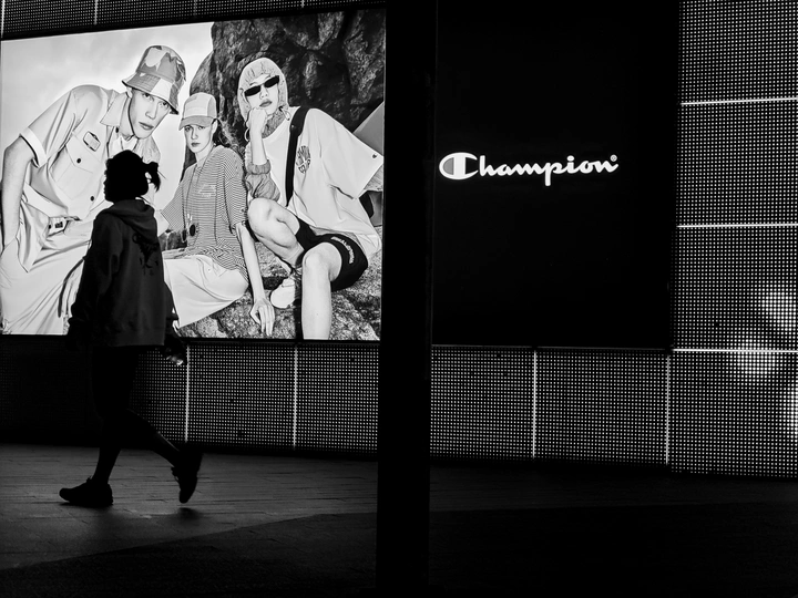 一张黑白照片 一对男女站在一面墙前的屏幕前行走。