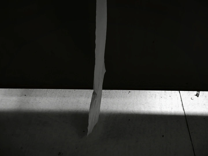 一个黑暗的房间 地板上铺着白纸 墙上有一把刀和一扇窗户。