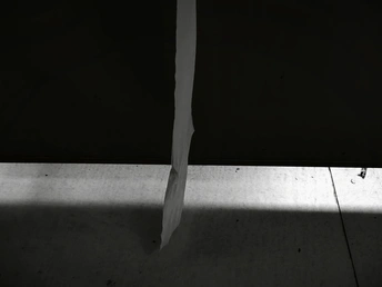 一个黑暗的房间 地板上铺着白纸 墙上有一把刀和一扇窗户。