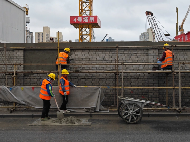 建筑工地 工人在墙上站立 背景中有起重机。