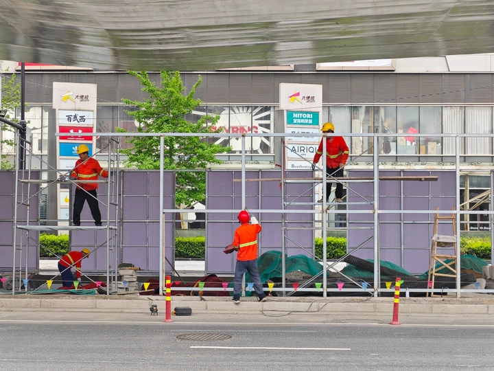 站在脚手架上的男人在建设中的大楼前