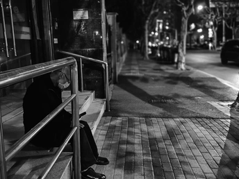 黑白色调 一个人坐在公交车站的长椅上 晚上 一个妇女在等公交车。