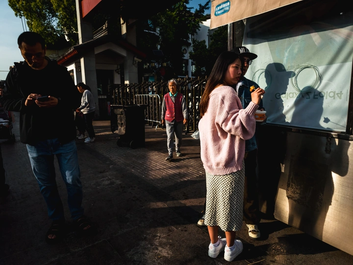 一个小女孩站在人行道上 旁边还有其他人。