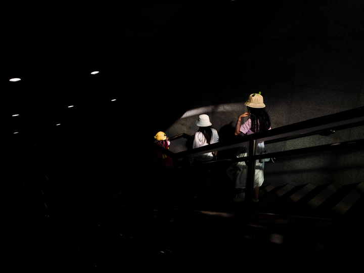 一个戴帽子的人在晚上站在楼梯上 楼梯上有灯光。