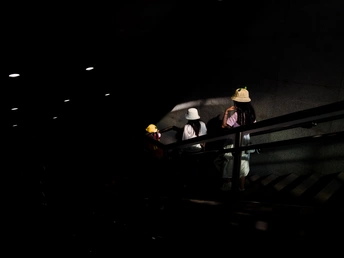 一个戴帽子的人在晚上站在楼梯上 楼梯上有灯光。