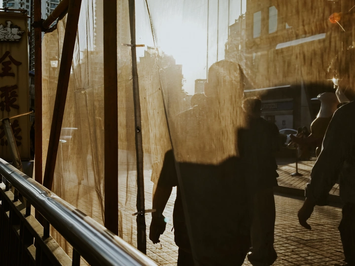 一个人和一个女人在穿过一座城市的桥上 背景是建筑物 手里拿着一把伞。