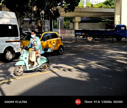 一个蓝色滑板车上的男子在街上行驶 与此同时 一个女摩托车手在公路上行驶。