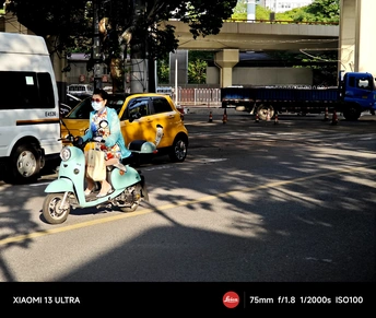 一个蓝色滑板车上的男子在街上行驶 与此同时 一个女摩托车手在公路上行驶。